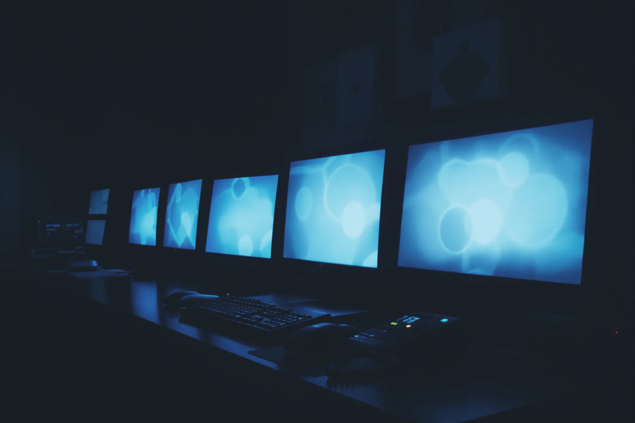 A security operator's desk at night with multiple monitors glowing cool blue.